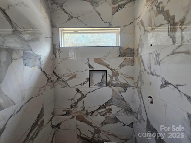 interior space featuring a marble finish shower and stone wall