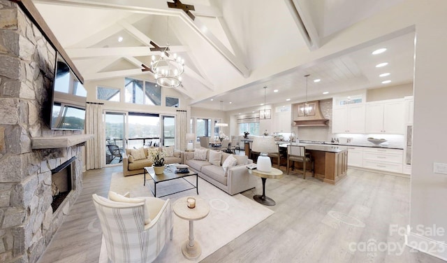 living room featuring an inviting chandelier, light hardwood / wood-style flooring, a fireplace, and beam ceiling