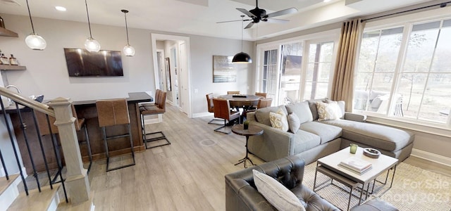 living room featuring a tray ceiling, ceiling fan, and light hardwood / wood-style flooring