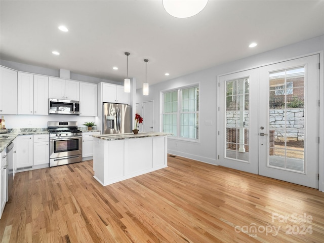 kitchen with white cabinetry, pendant lighting, appliances with stainless steel finishes, and a kitchen island