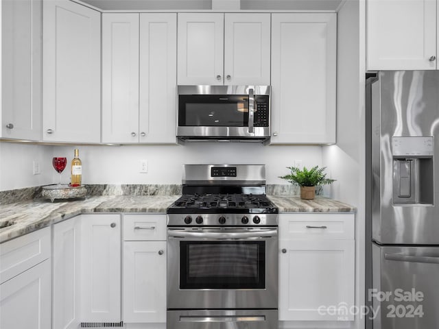 kitchen featuring white cabinets, appliances with stainless steel finishes, and light stone counters