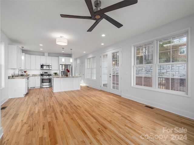 kitchen with decorative light fixtures, a kitchen island, sink, stainless steel appliances, and white cabinets