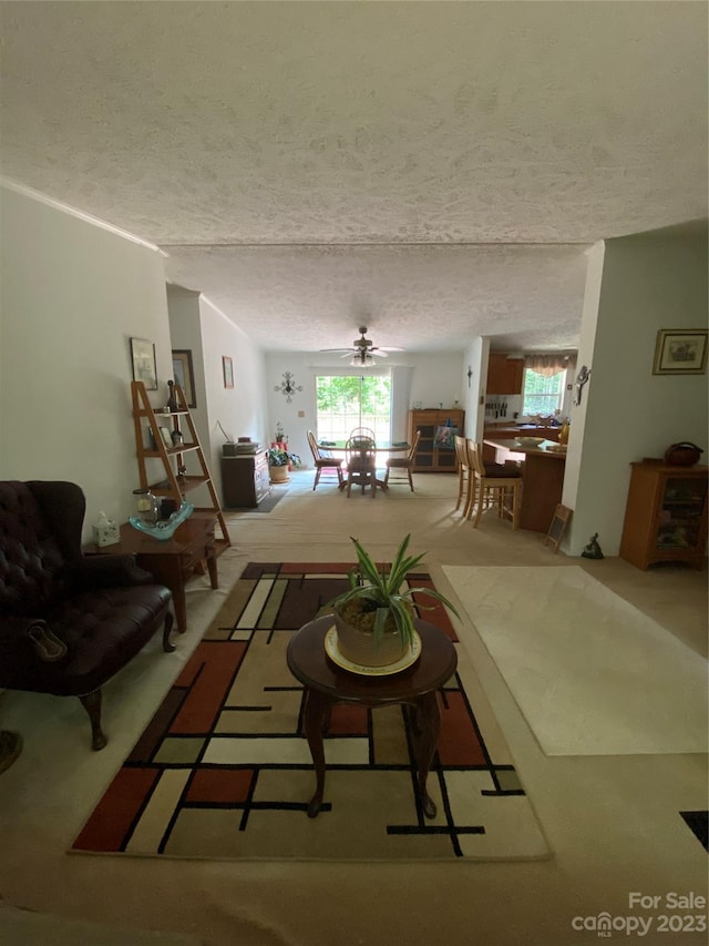 unfurnished living room with a textured ceiling, light colored carpet, and ceiling fan