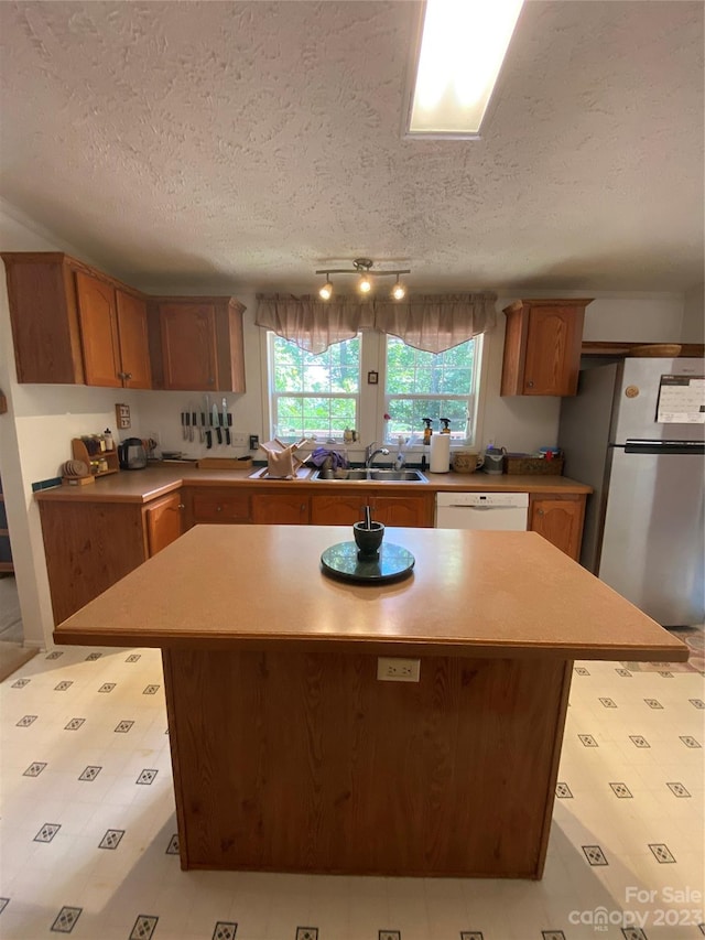 kitchen featuring stainless steel refrigerator, a textured ceiling, a center island, and light tile flooring