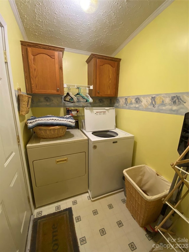 clothes washing area featuring cabinets, crown molding, washing machine and clothes dryer, and light tile flooring