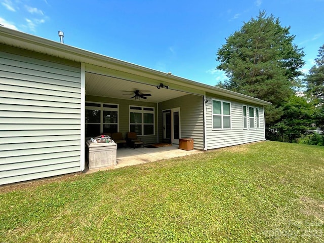 rear view of property with a yard, ceiling fan, and a patio