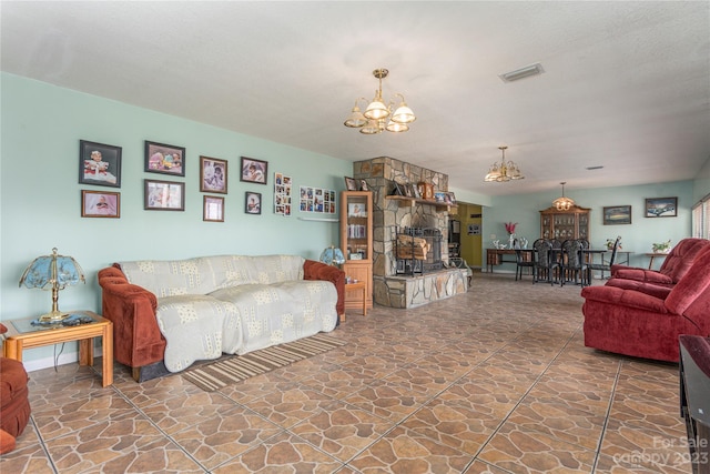 tiled living room featuring an inviting chandelier, a textured ceiling, and a stone fireplace