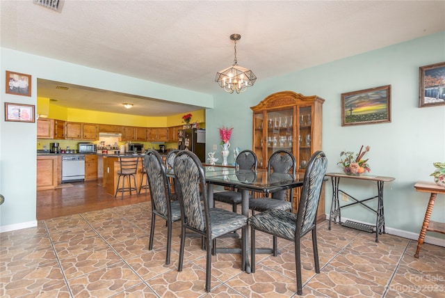 tiled dining space featuring a textured ceiling and a notable chandelier