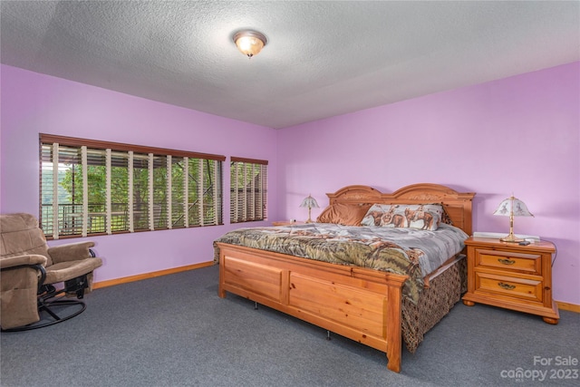 bedroom with dark colored carpet and a textured ceiling