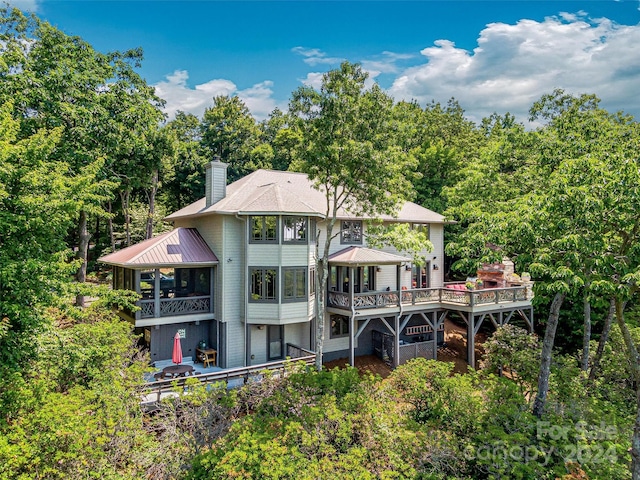 rear view of property featuring a sunroom and a wooden deck