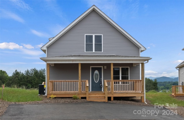 view of front of house with central air condition unit, a mountain view, and covered porch