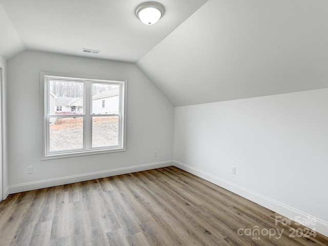 additional living space featuring light wood-type flooring and vaulted ceiling