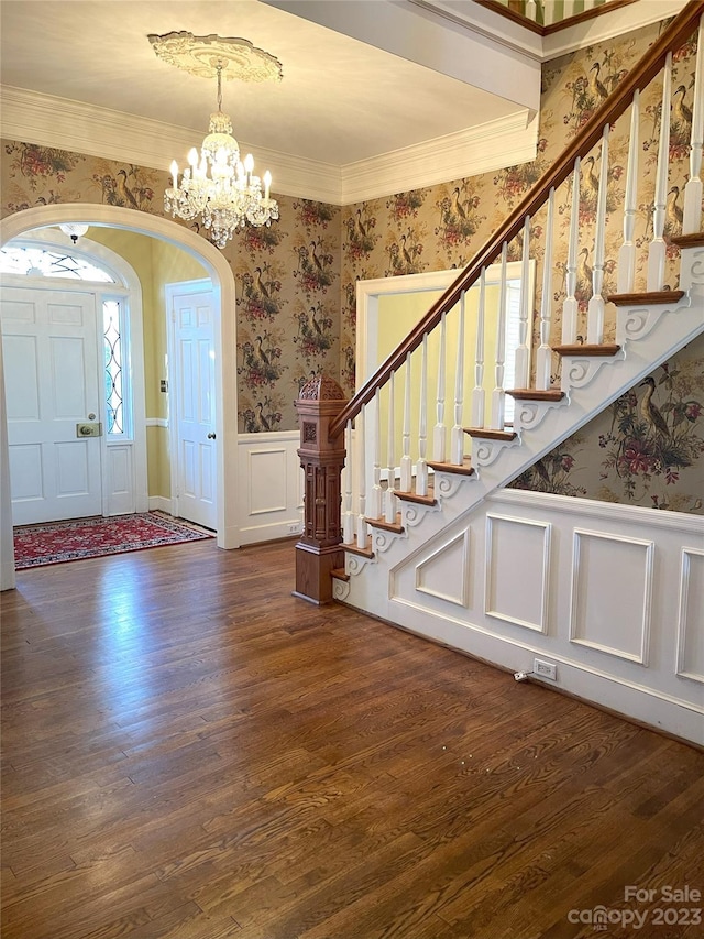 entrance foyer featuring dark hardwood / wood-style flooring, ornamental molding, and an inviting chandelier