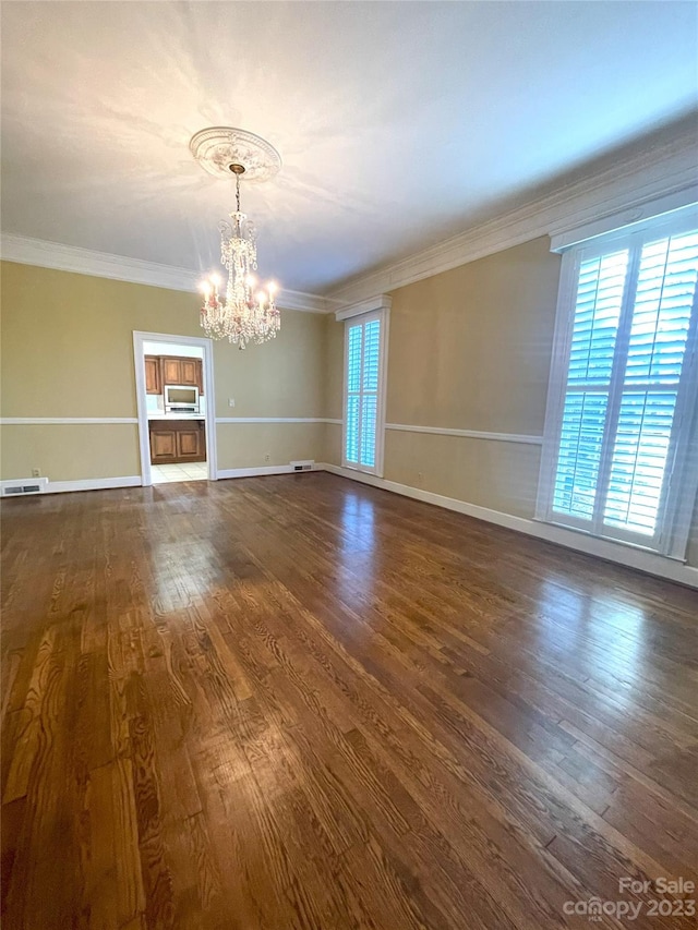 spare room featuring a chandelier, dark hardwood / wood-style floors, and crown molding