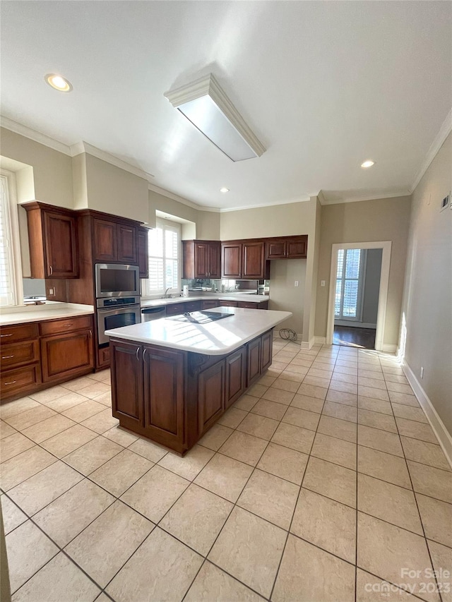 kitchen featuring light tile floors, a center island, a healthy amount of sunlight, and stainless steel appliances