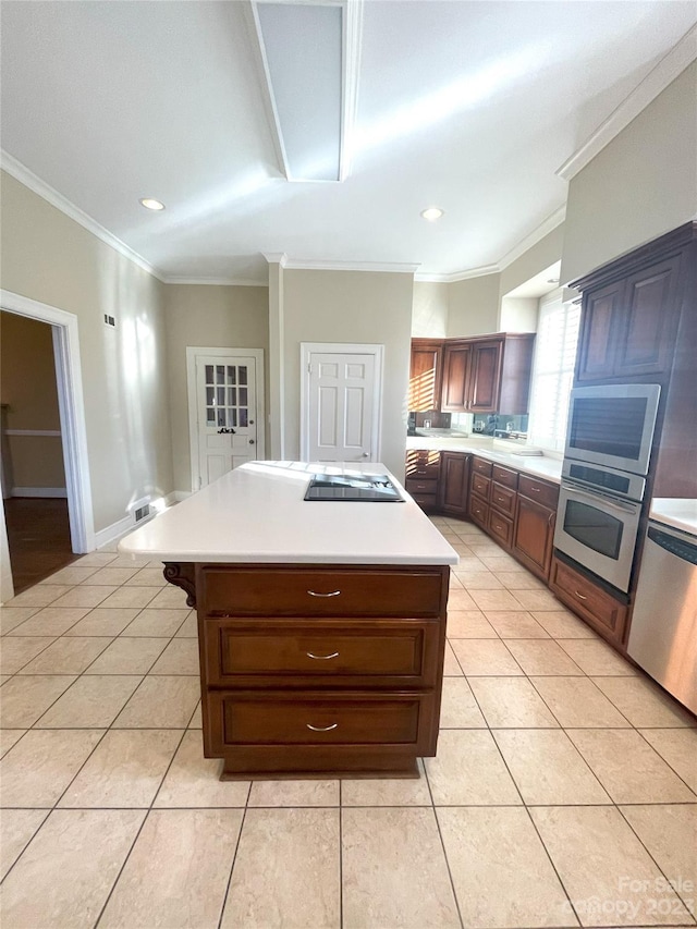 kitchen with crown molding, a kitchen island, appliances with stainless steel finishes, and light tile floors