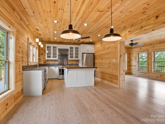 kitchen featuring appliances with stainless steel finishes, light wood-type flooring, wooden ceiling, a healthy amount of sunlight, and white cabinets