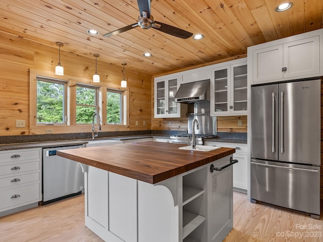 kitchen with light hardwood / wood-style flooring, stainless steel appliances, wooden counters, and a center island with sink