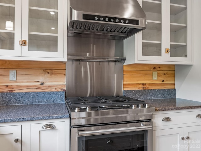 kitchen featuring white cabinets, dark stone counters, high end stainless steel range, and wall chimney range hood