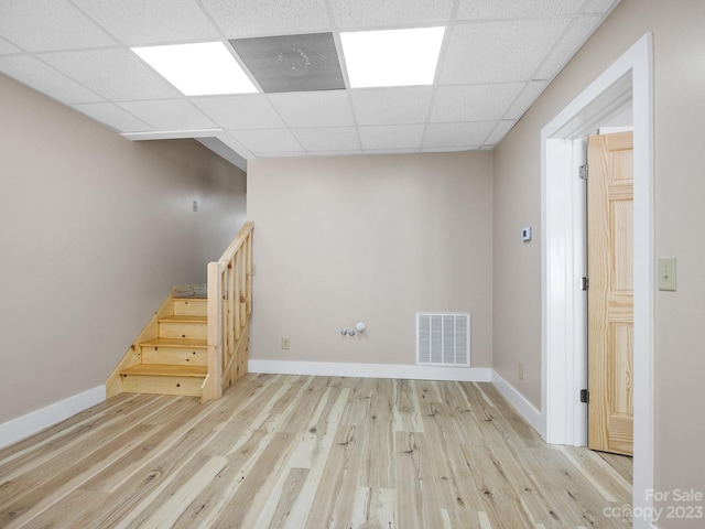 basement with a drop ceiling and light hardwood / wood-style floors