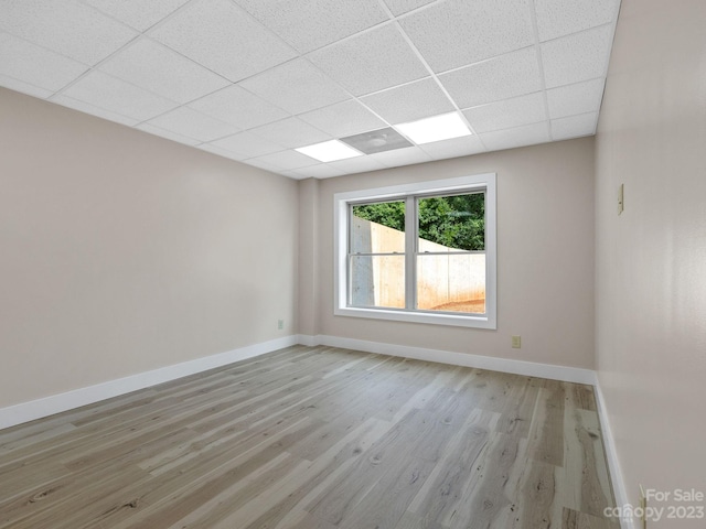 empty room with a paneled ceiling and light wood-type flooring