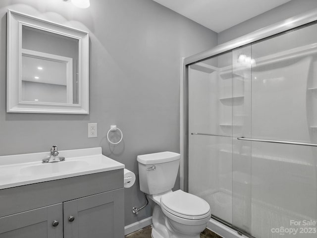 bathroom with toilet, vanity with extensive cabinet space, and a shower with shower door