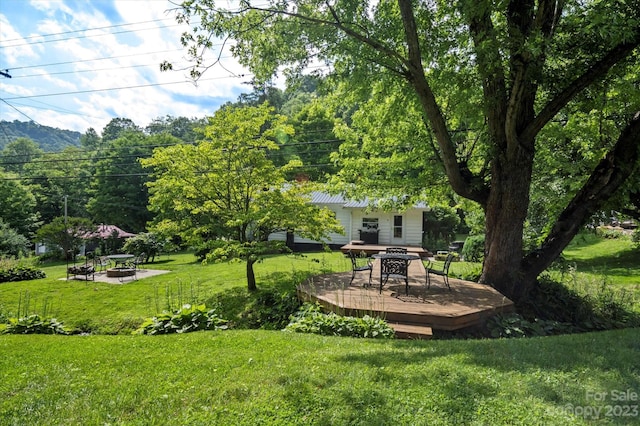 view of yard with a deck and an outdoor fire pit