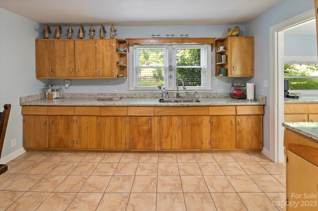 kitchen with light tile flooring, light stone countertops, and sink