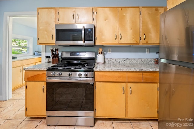 kitchen featuring light stone counters, appliances with stainless steel finishes, and light tile floors