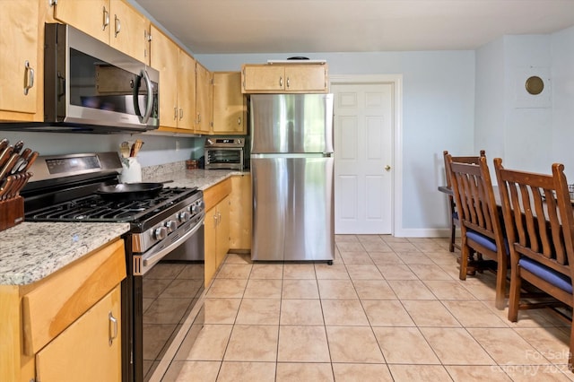 kitchen featuring light tile floors, stainless steel appliances, and light stone countertops