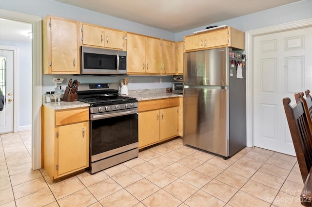 kitchen with light stone counters, light tile floors, and stainless steel appliances