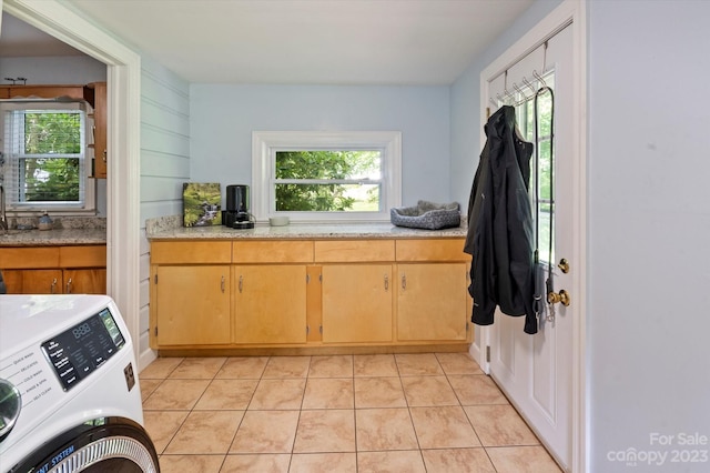 kitchen featuring light tile floors, light stone countertops, and washer / dryer