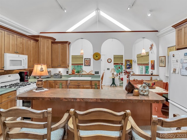 kitchen featuring pendant lighting, a breakfast bar area, white appliances, vaulted ceiling, and rail lighting