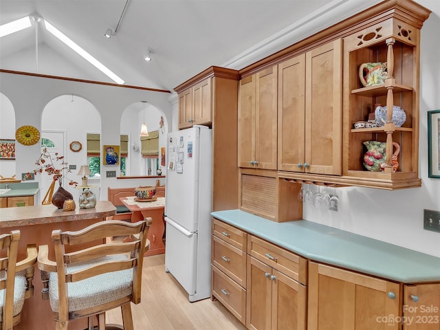 kitchen with white fridge, light hardwood / wood-style floors, a kitchen bar, pendant lighting, and lofted ceiling