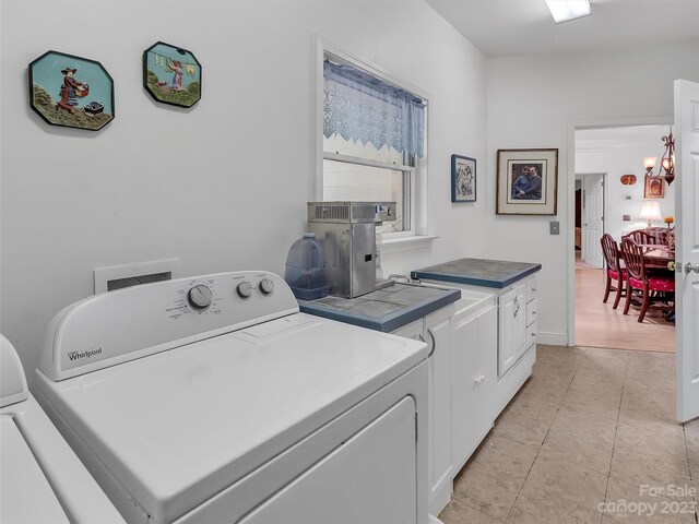 laundry area with light hardwood / wood-style flooring, washing machine and dryer, and a notable chandelier