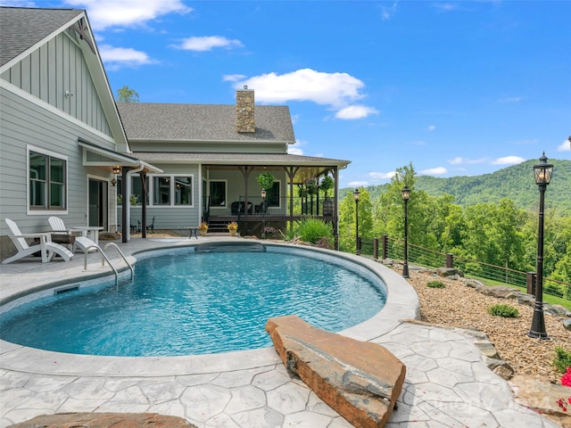 view of swimming pool with a sunroom, a mountain view, and a patio