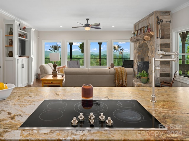 kitchen featuring ceiling fan, a wood stove, ornamental molding, and black electric cooktop