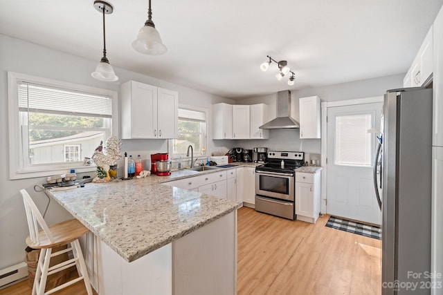 kitchen with decorative light fixtures, appliances with stainless steel finishes, a kitchen bar, light stone counters, and wall chimney exhaust hood