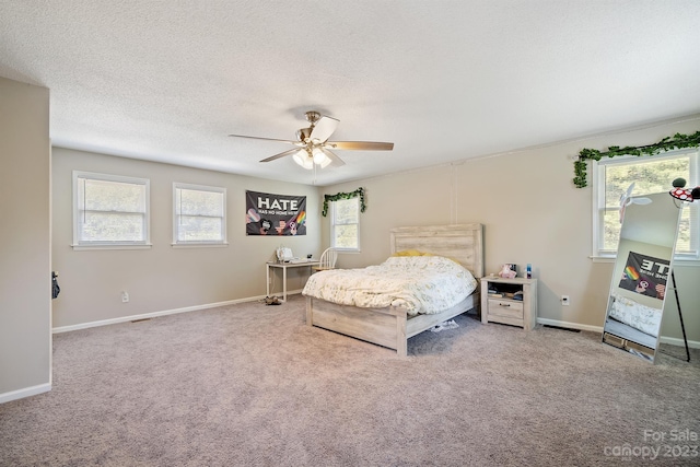 bedroom featuring ceiling fan, a textured ceiling, light carpet, and multiple windows