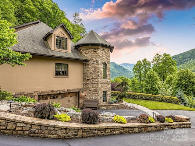 202 Emerald Ln, Maggie Valley, NC 28751 - property exterior at dusk featuring stucco siding, stone siding, a garage, asphalt driveway, and a mountain view