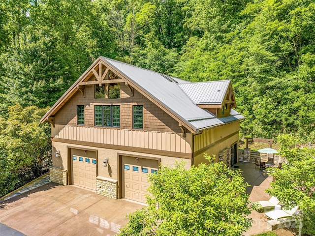 202 Emerald Ln, Maggie Valley, NC 28751 - view of front facade featuring stone siding, an attached garage, driveway, and a forest view