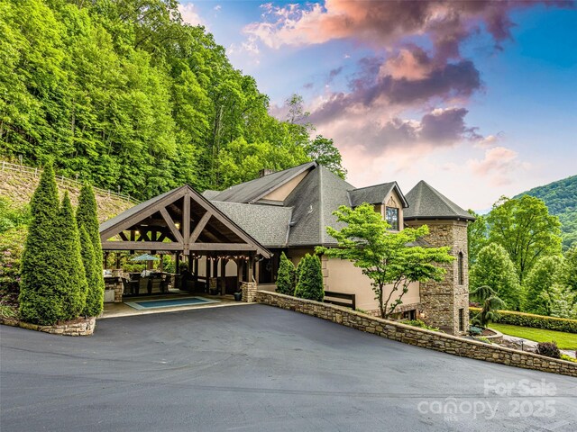 202 Emerald Ln, Maggie Valley, NC 28751 - view of front of property with asphalt driveway, stone siding, a shingled roof, a patio, and stucco siding