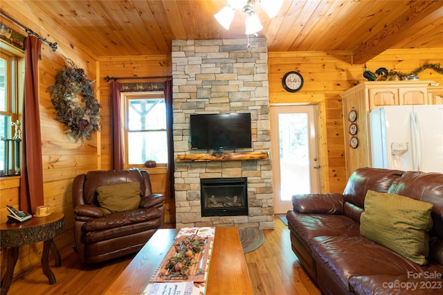 living room featuring wooden walls, a fireplace, wooden ceiling, and light hardwood / wood-style floors