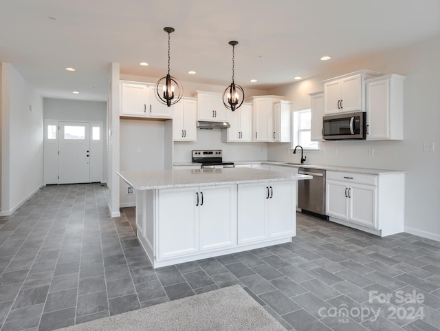 kitchen featuring decorative light fixtures, stainless steel appliances, a kitchen island, and white cabinetry