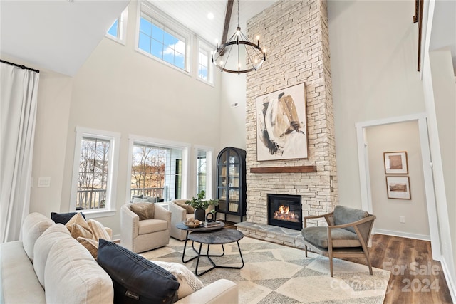 living room featuring a fireplace, hardwood / wood-style floors, a towering ceiling, and a notable chandelier