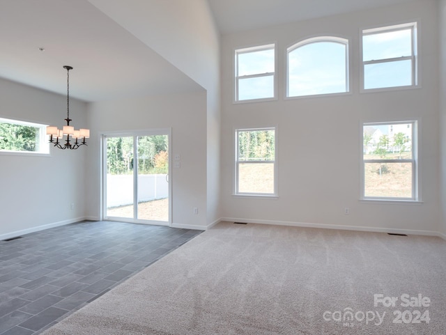 unfurnished living room featuring a chandelier, a towering ceiling, and dark colored carpet