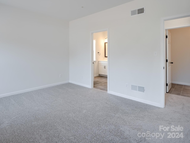 unfurnished bedroom featuring connected bathroom and light colored carpet