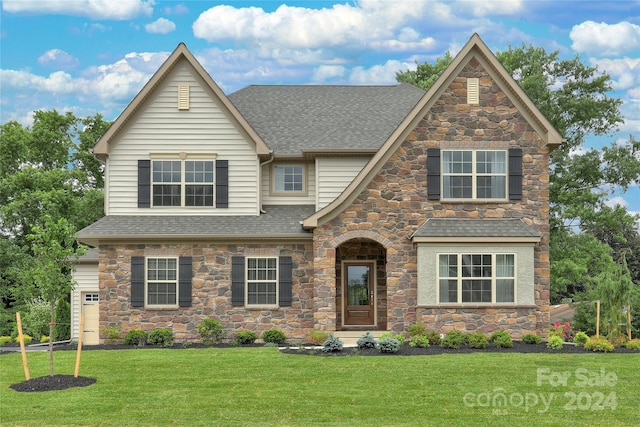 view of front facade with a front lawn and a shingled roof