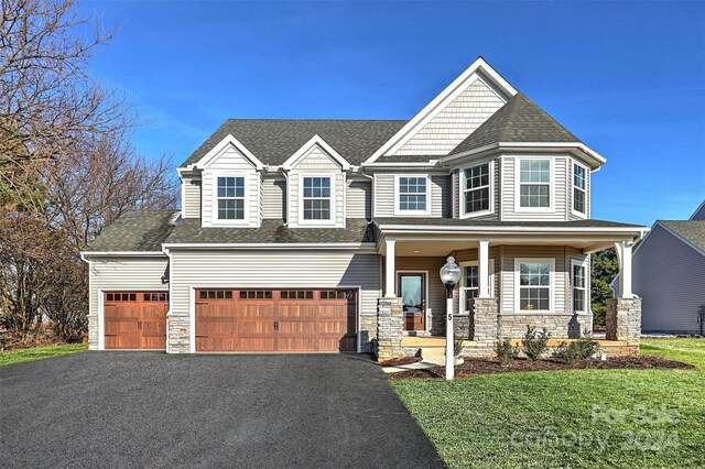 view of front of house featuring a porch, a garage, and a front lawn