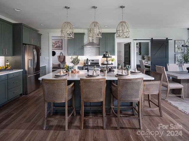 kitchen with hanging light fixtures, a barn door, dark wood-type flooring, and appliances with stainless steel finishes